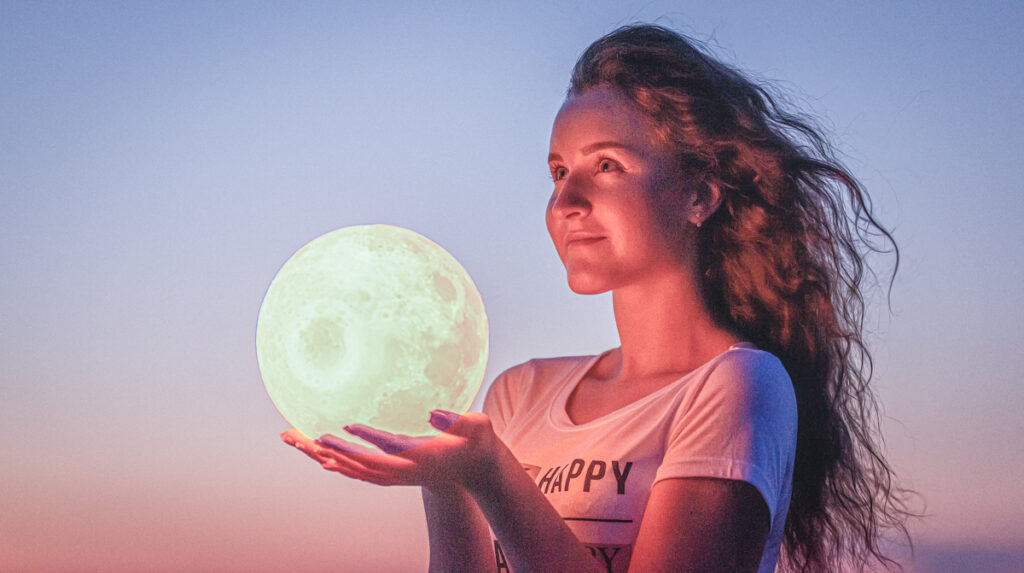 A young woman holds the full moon in her hands